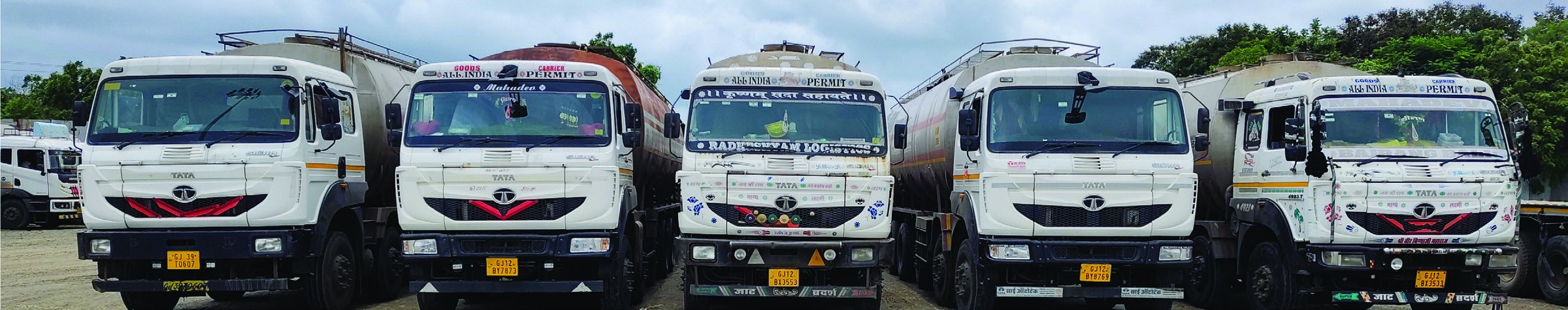 A row of Radha Shyam Logistics tankers parked in the yard